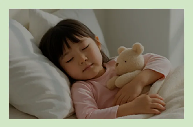 ベッドに横になり、ぬいぐるみを抱いている子どもの写真