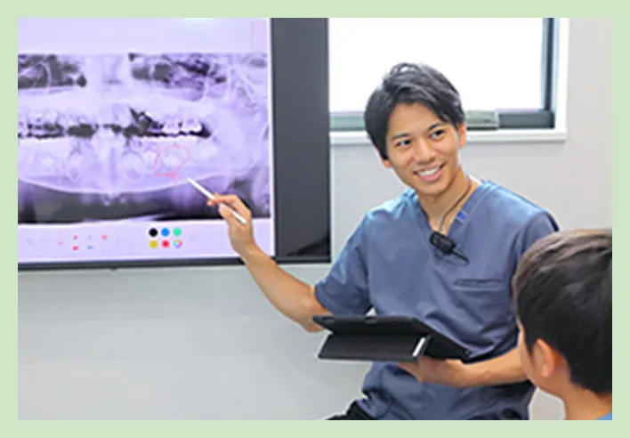 歯科医師がレントゲン画像を指しながら説明している様子